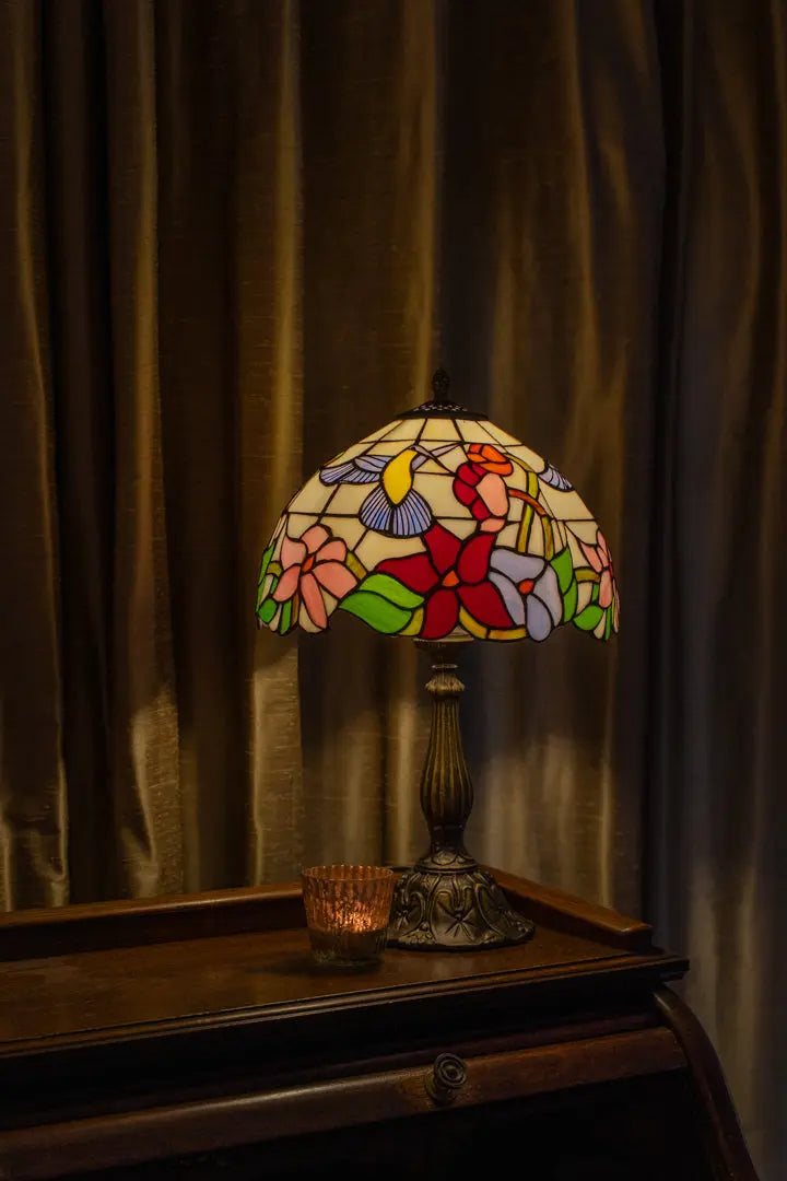 ChatGPT zei: Tiffany tafellamp met warme amber- en groentinten op een dressoir, werpt een zachte kleurrijke gloed op de muur en brengt warmte en nostalgie in huis.
