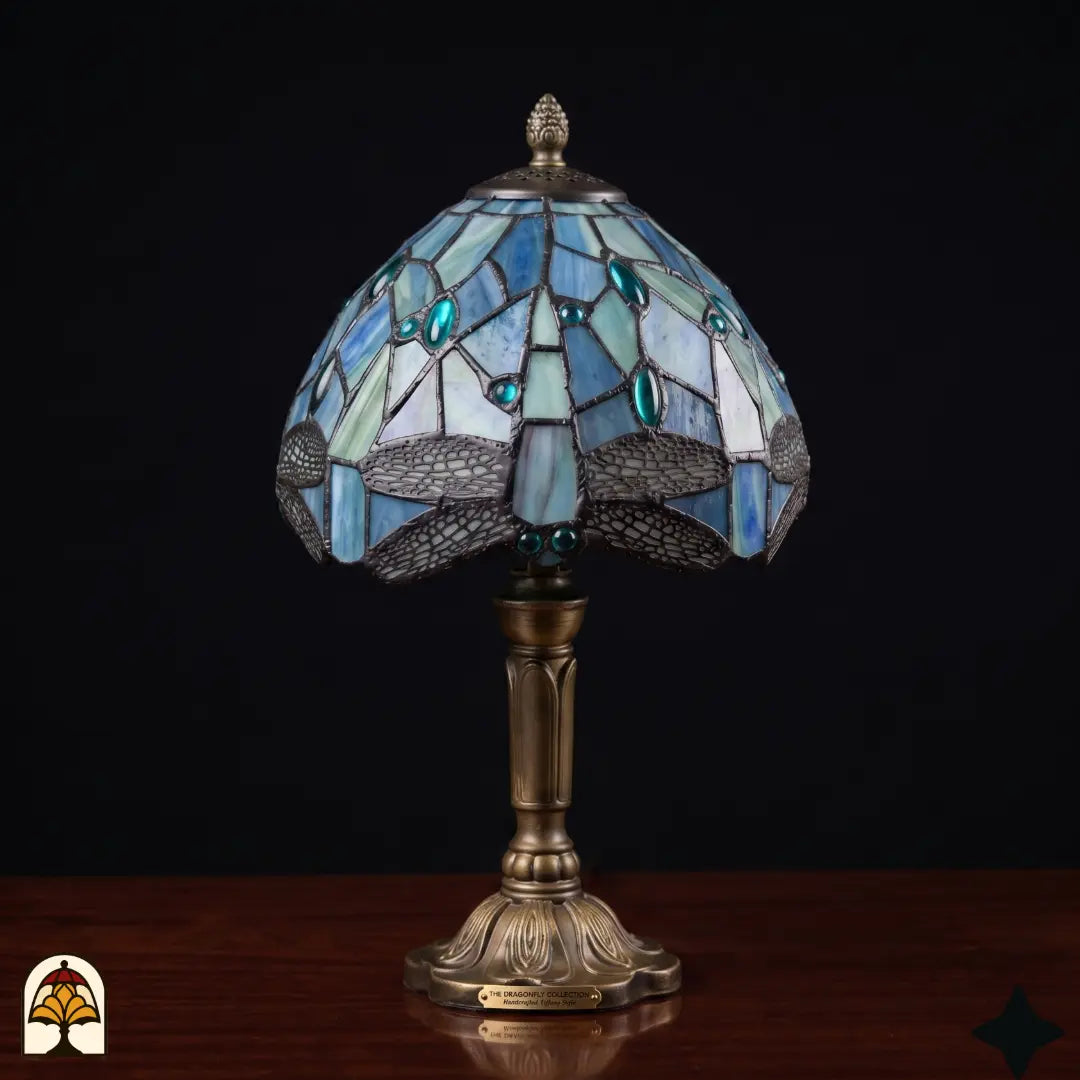 Onverlichte Tiffany tafellamp Libellula Celeste ⌀20 cm op houten tafel – blauwe glas-in-lood kap met libellenmotief en turquoise juwelen, bronzen kolomvoet