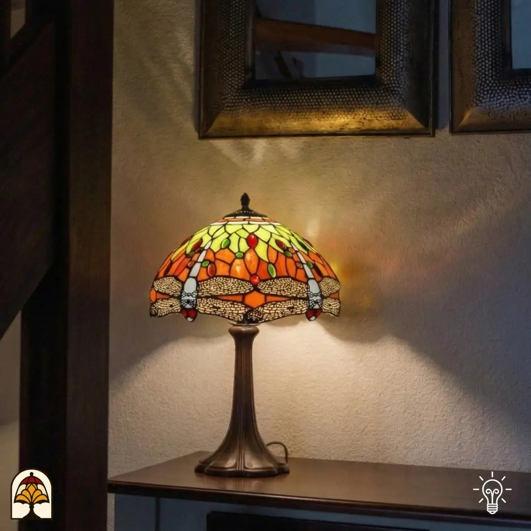 Verlichte Tiffany tafellamp Libellula Azul ⌀30 op consoletafel tegen gestructureerde witte wand, warm oranje licht op wand, spiegel met houten lijst op achtergrond