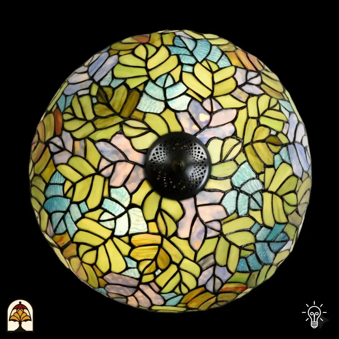 Bovenaanzicht verlichte koepelkap Tiffany tafellamp Sylva Verde, geel-groene, lichtblauwe, roze en oranje bladmotieven in glas-in-lood, centrale bronzen fitting zichtbaar