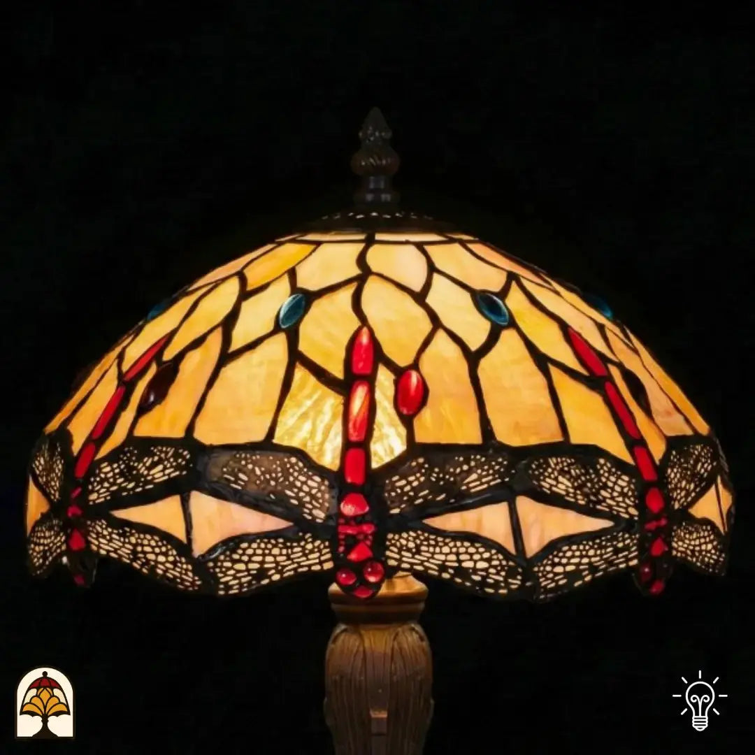 Close-up verlichte kap Tiffany tafellamp Libelle Elegance, geel-amber glas-in-lood met rode druppels en blauwe accenten, libellenmotieven langs de rand