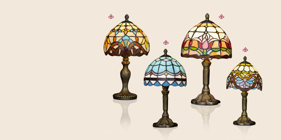 Afbeelding van vier Tiffany-stijl tafellampen met glas-in-lood kappen in verschillende kleuren en patronen, geplaatst op een lichte beige achtergrond.