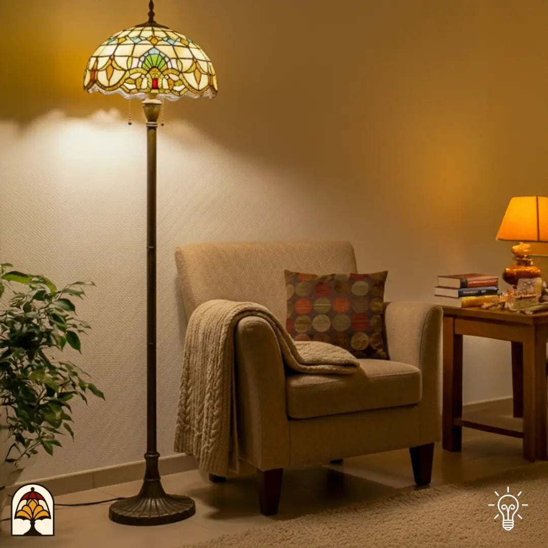 Tiffany vloerlamp Barok verlicht in woonkamer — naast beige fauteuil met deken en kussen, groene plant links, bijzettafel met boeken rechts