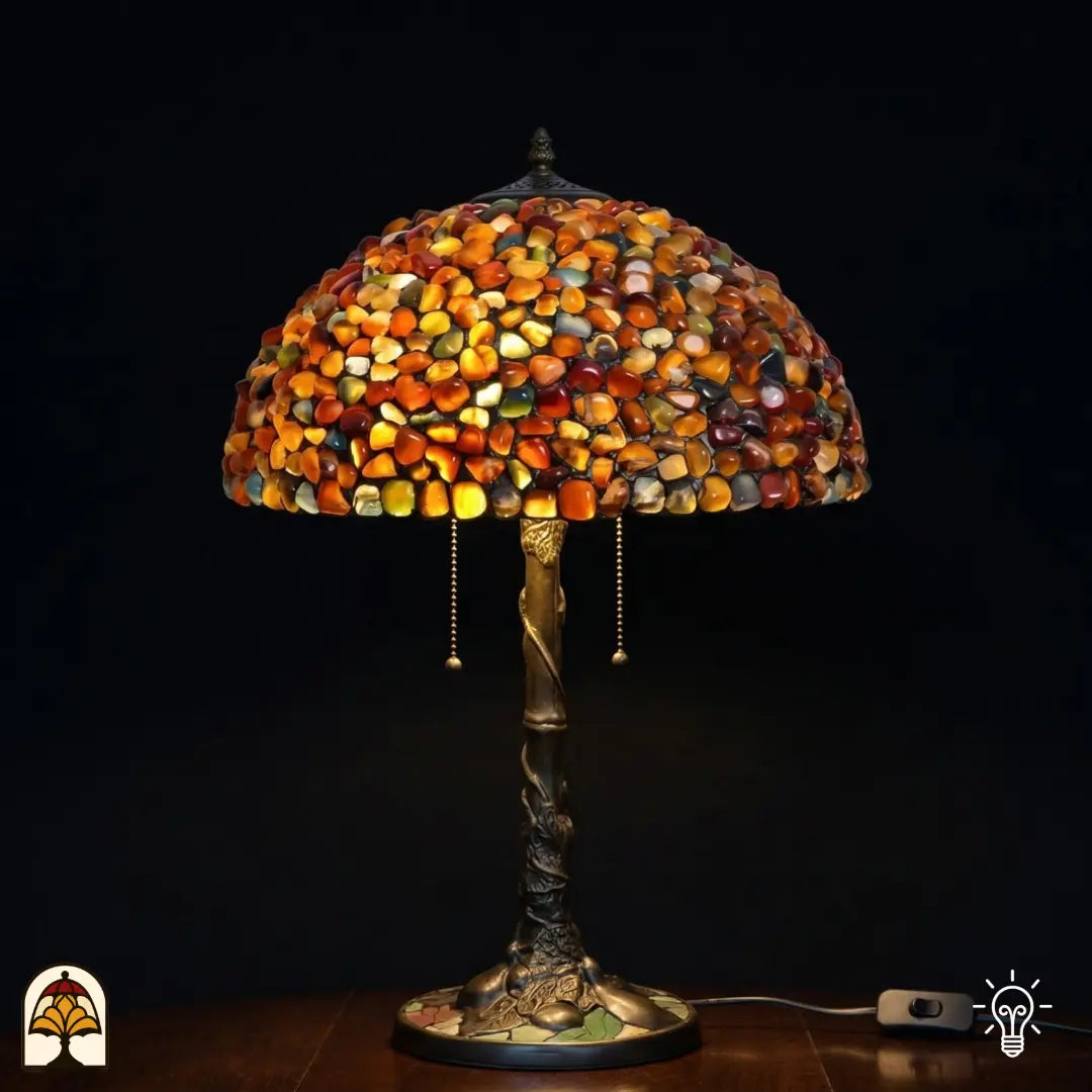 Verlichte Tiffany tafellamp Stone Mosaic Amber ⌀40 cm op donkere achtergrond – koepelkap van amber, oranje en okerkleurige gepolijste stenen, bronzen boomstamvoet met twee trekschakelaars
