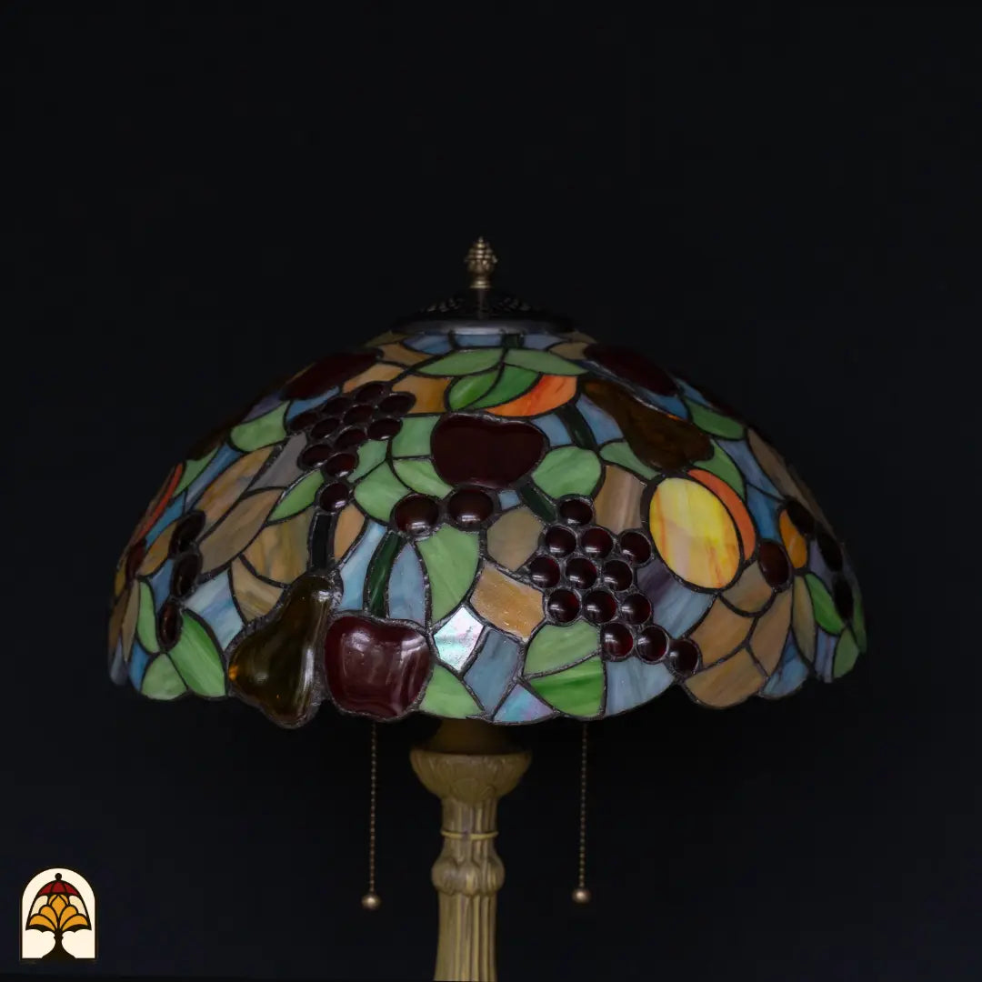 Close-up kap Tiffany tafellamp Frutta Viva onverlicht — paarse druiven, donkerrode appels, groene peer, groene bladeren, blauwe vlakken