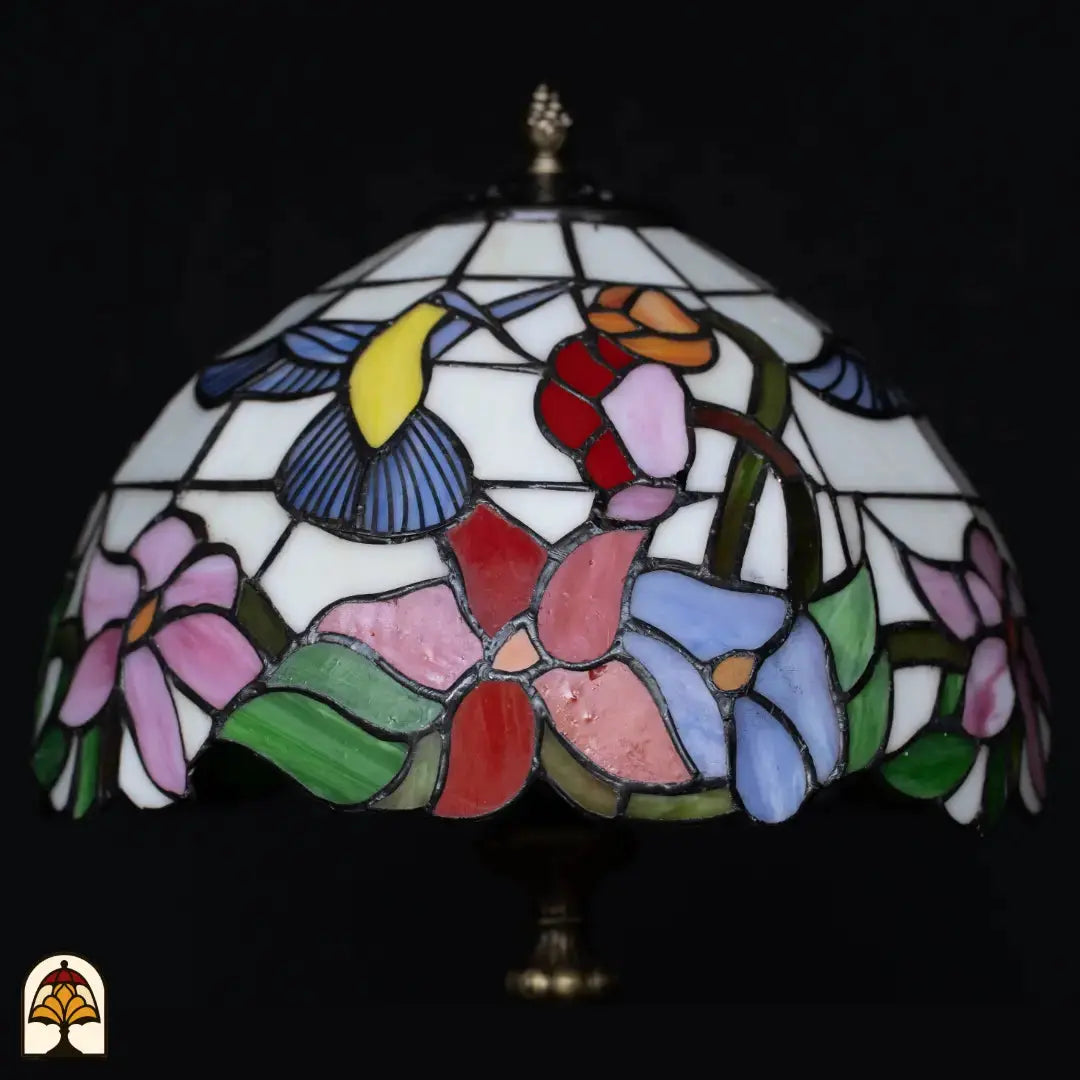Close-up kap Tiffany tafellamp Colibrì onverlicht — wit glas met kolibrie (geel/blauw), rode, oranje, roze en blauwe bloemen, groene bladeren
