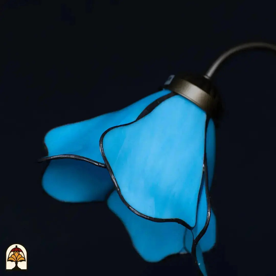 Close-up onverlichte blauwe lotusbloem kap — opwaaierende blauwe glazen bloemblaadjes, donkere achtergrond