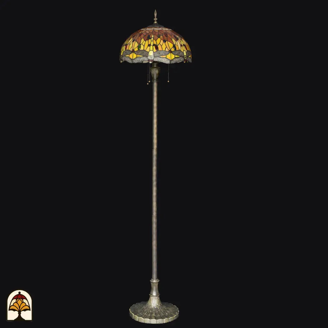 Tiffany vloerlamp Libellula Aurea onverlicht op zwarte achtergrond — amber/geel/bruine kap met libellenrand, lange paal met brede voet