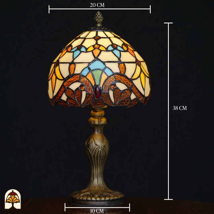Afmetingen van klassieke Tiffany-stijl tafellamp met sierlijke bronzen voet en glas-in-lood kap in geel-, blauw- en bruintinten, tegen een zwarte achtergrond.