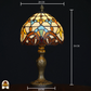 Afmetingen van klassieke Tiffany-stijl tafellamp met sierlijke bronzen voet en glas-in-lood kap in geel-, blauw- en bruintinten, tegen een zwarte achtergrond.