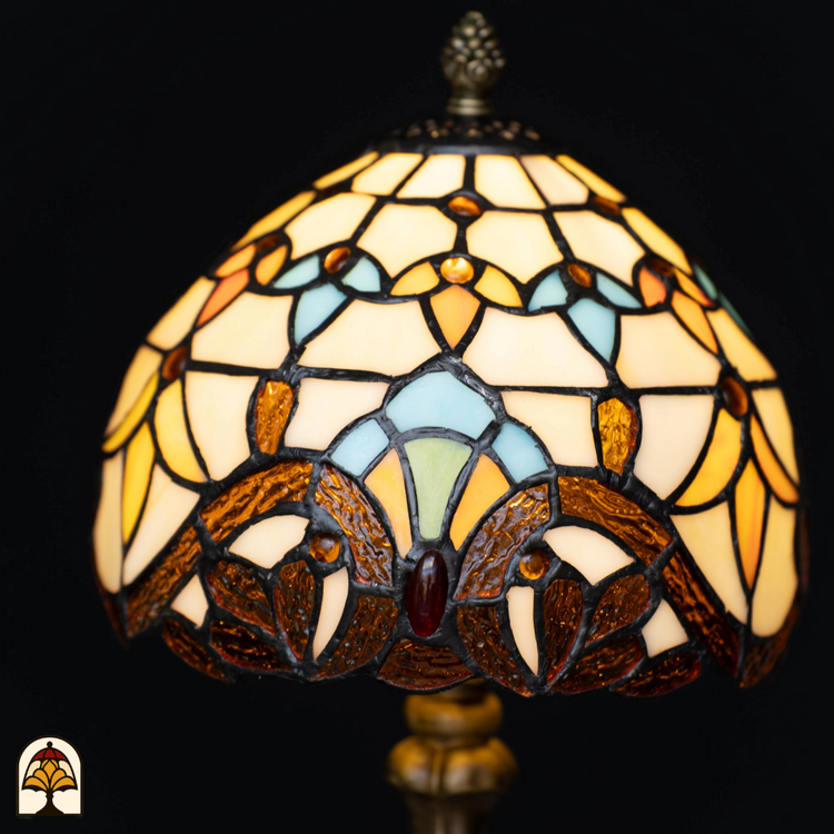 Gedetailleerde close-up van een Tiffany-stijl lampenkap met glas-in-lood in warme geel-, oranje-, blauw- en bruintinten, op een zwarte achtergrond
