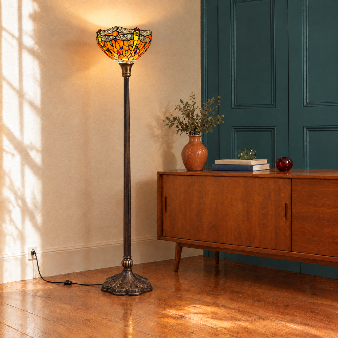 Tiffany vloerlamp Libellula Tramonto ⌀30 cm – sfeerfoto als uplighter naast houten dressoir en groene deur in de woonkamer