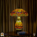 Tiffany lamp tafellamp verlicht op houten tafel met gordijn op de achtergrond, amberkleurige kap met libellemotieven en blauwe glaskralen, glas-in-lood peervormige voet en bronzen leeuwenpootvoet