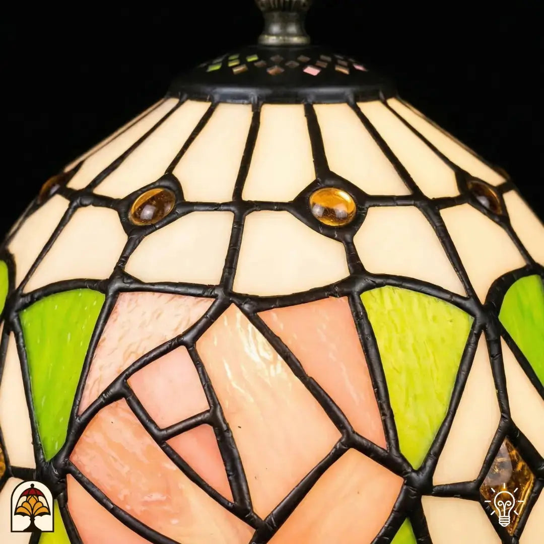 Close-up verlichte kap Tiffany tafellamp Rosalia Verde, witte bovenkap met gouden ronde accenten, roze roos en groene bladeren in glas-in-lood