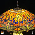 Detailopname van tiffany lamp kapbovenzone verlicht, amberkleurig glas met blauwe en groene ovale glaskralen in een band en rode ronde kralen, bronzen ventilatieplaat en puntfinial bovenaan