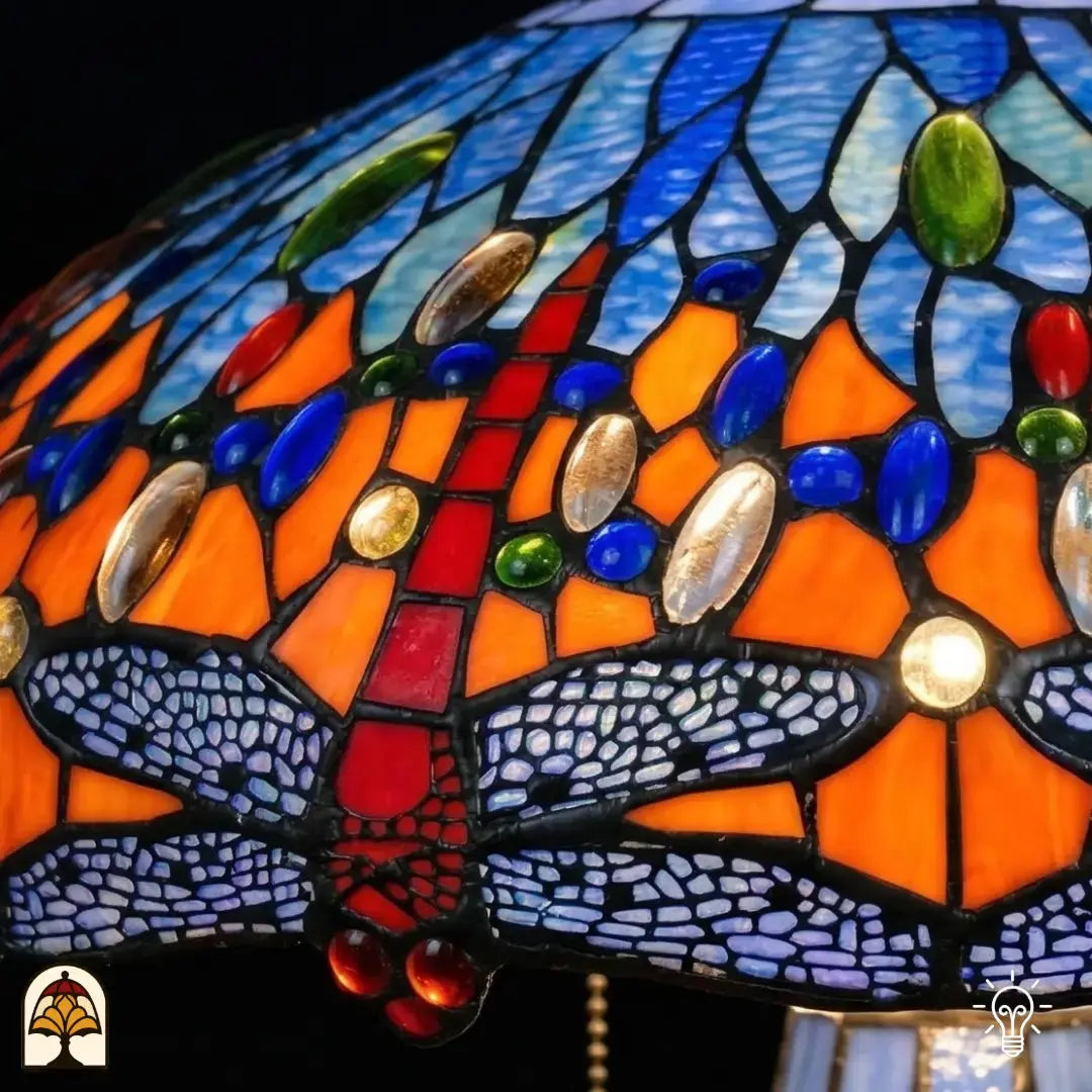 Detailopname van tiffany lamp libelle-rand onderaan de kap verlicht, lavendelblauw-witte libellen met geaderde vleugels in glas-in-lood, rode libellen zichtbaar, blauwe en amber glaskralen