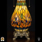 Detailopname van tiffany lamp glas-in-lood peervormige voet verlicht, amberkleurig glas met groene, blauwe en bruine ovale glaskralen, bronzen siervoet met leeuwenpoten en acanthusrolwerk
