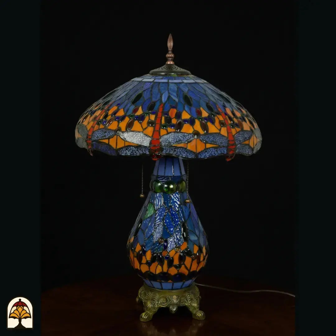 Tiffany lamp tafellamp onverlicht, koepelvormige kap met blauw glas en libellemotieven langs de rand, oranje en rode glaskralen, peervormige blauwe glas-in-lood voet en bronzen leeuwenpootvoet
