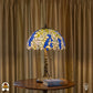 Verlichte Tiffany tafellamp Wisteria Celeste op ronde houten tafel voor gordijnen met boek ernaast, blauwe en witte glyciniabloemen oplichtend