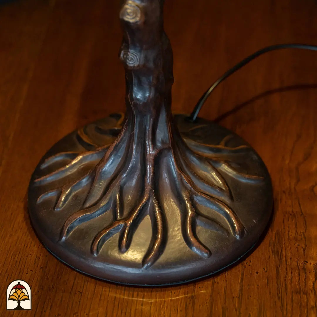 Close-up bronzen boomstam voet Wisteria Celeste met uitgewaaierde wortels op ronde basis, aansluitsnoer zichtbaar