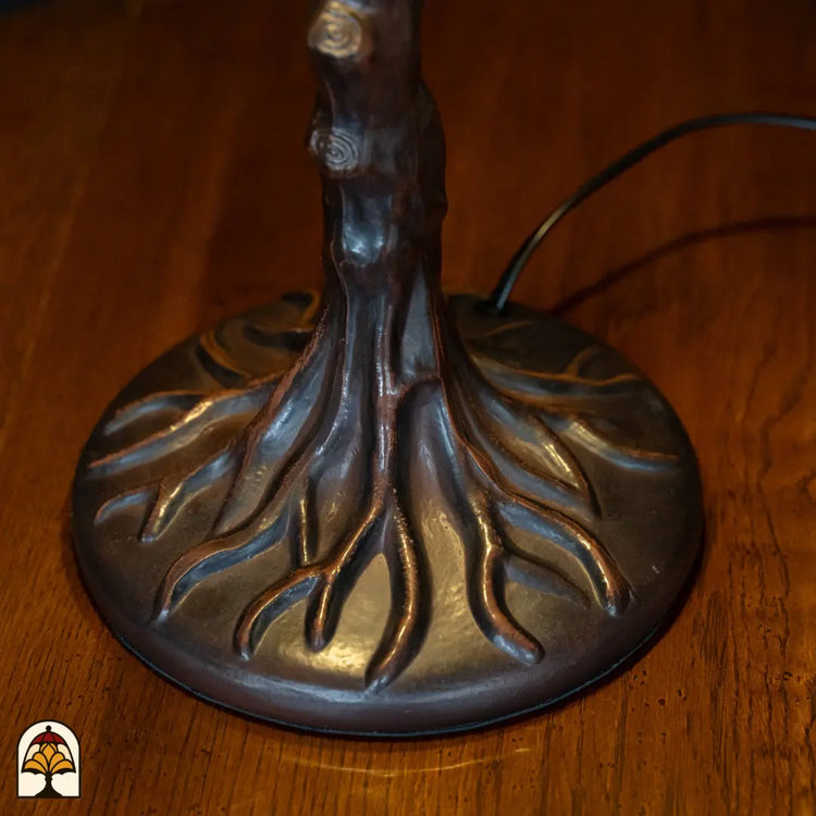Close-up bronzen boomstam voet Wisteria Celeste met uitgewaaierde wortels op ronde basis, aansluitsnoer zichtbaar