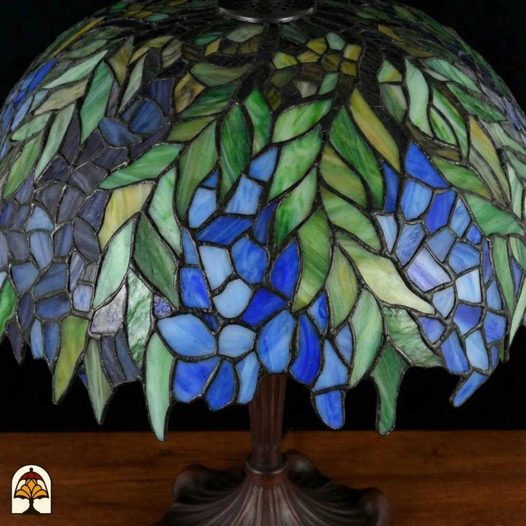 Close-up onverlichte Tiffany kap — groene bladeren, blauwe en paarse bloemen in wisteria-stijl