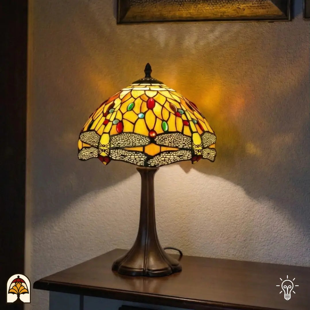 Verlichte Tiffany tafellamp Libellula Aurea ⌀30 op consoletafel in hoekopstelling, warm geel-oranje licht op gestructureerde witte wand