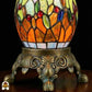 Close-up bronzen siervoet Libellula Lumina ⌀30 met glas-in-lood bolvoet, oranje en groene panelen met gekleurde juwelen, bronzen voetstuk met acanthusblad- en krulmotieven en leeuwenpoten