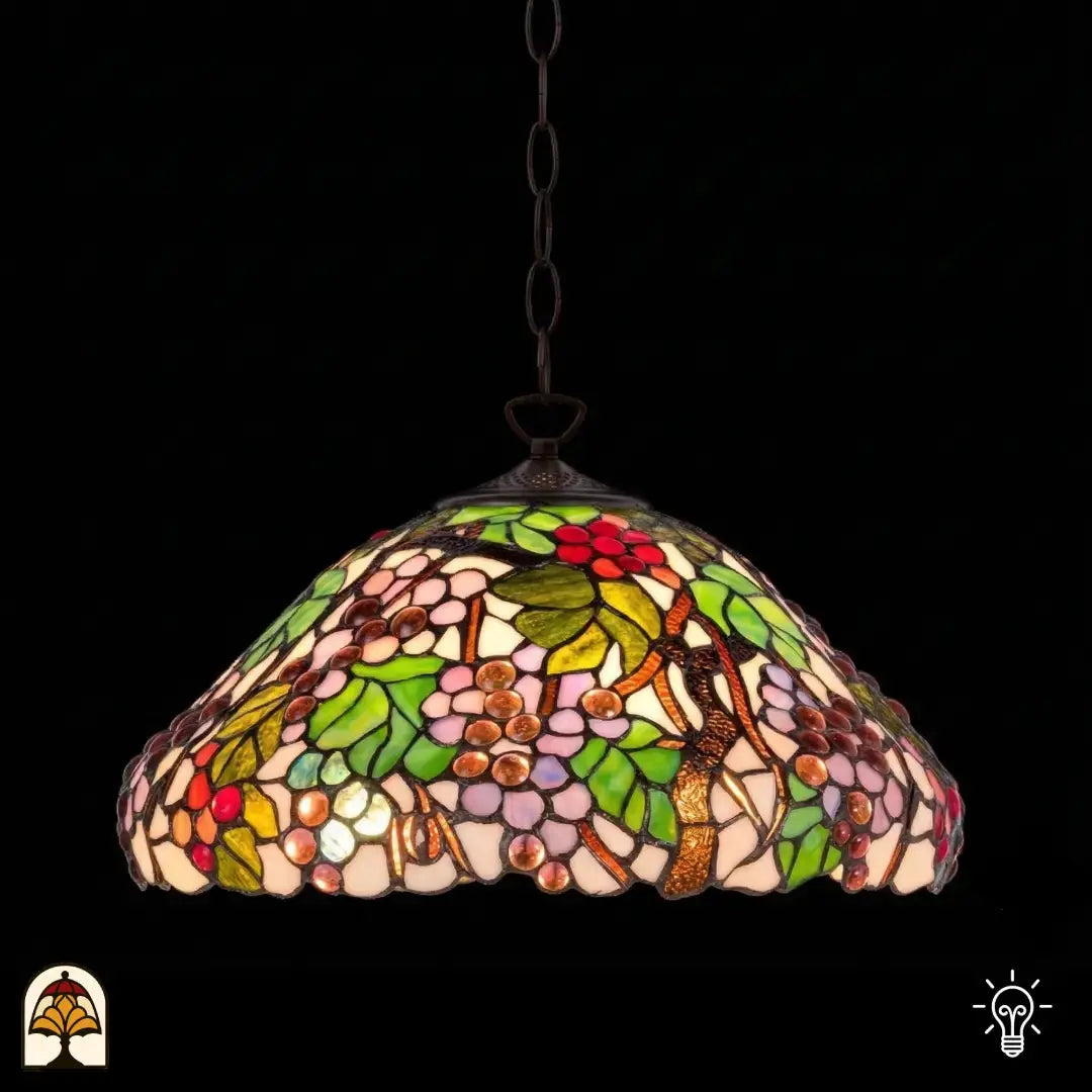 Verlichte Tiffany hanglamp Sylva Berria, koepelvormige kap met wijnrankmotieven, rode, lila en roze druivenkorrels en groene bladeren in glas-in-lood, donkere achtergrond