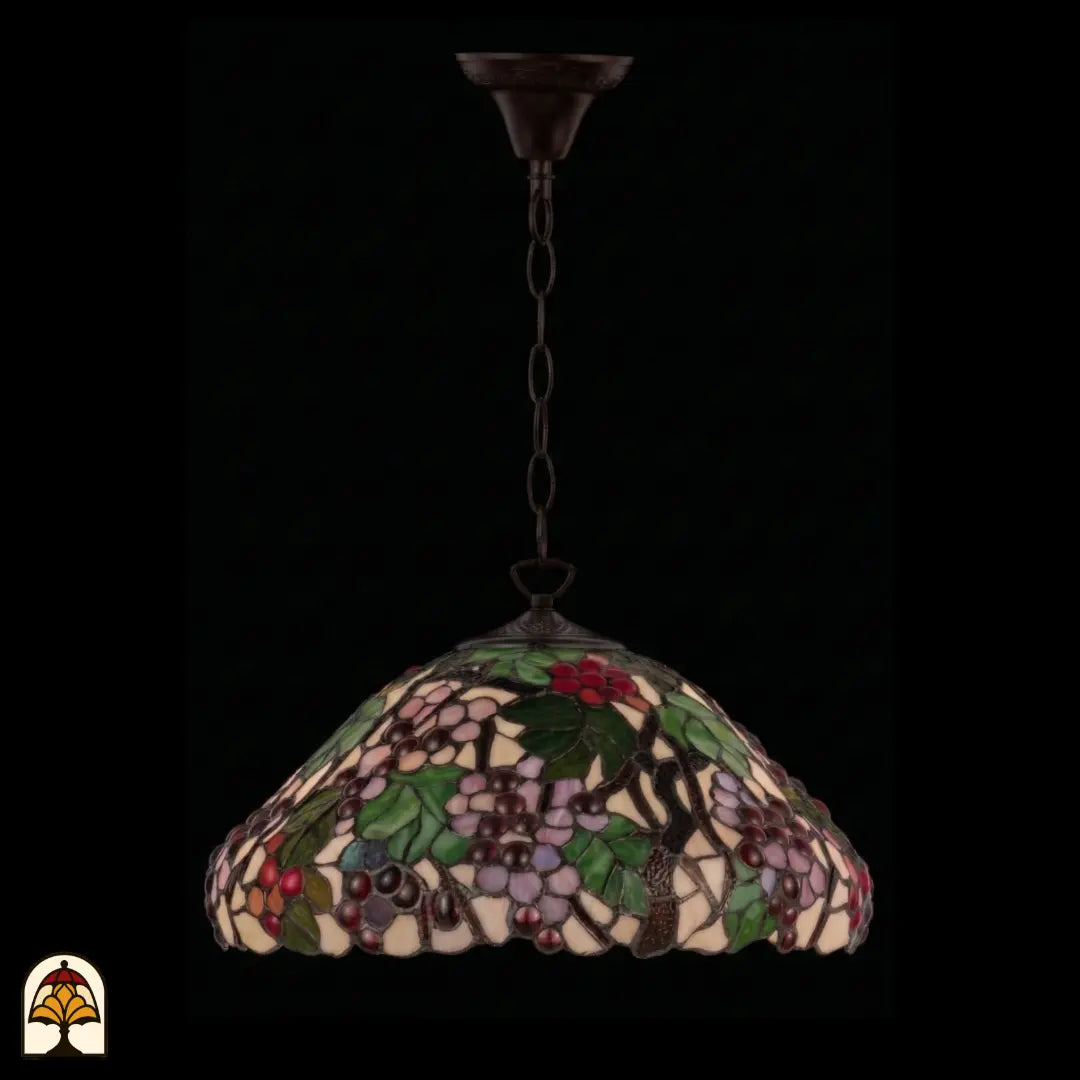 Onverlichte Tiffany hanglamp Sylva Berria aan bronzen ketting vanuit andere hoek, koepelvormige kap met lila en rode druiventrosjes en groene bladeren