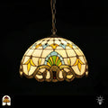 Verlichte Tiffany hanglamp Barok ⌀40, crème kap met gele tulpmotieven, blauwe en groene waaiermotief, gouden rolwerkrand langs rand, bronzen ketting, donkere achtergrond