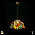 Tiffany lamp hanglamp verlicht, koepelvormige glas-in-lood kap met oranje-gele rozen, rode ovale glaskralen en groene bladeren op witte achtergrond, gekartelde rand, opgehangen aan bronzen ketting met sierlijke plafondrozet