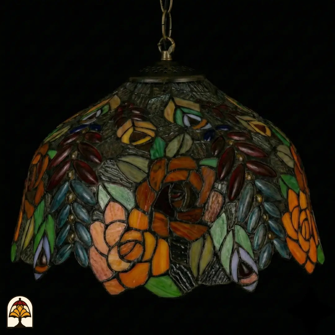 Tiffany lamp hanglamp onverlicht van dichterbij, koepelvormige kap met oranje, bruine en roze rozen, grijsgroen getextureerd glas en gekleurde bladeren en ovale glaskralen