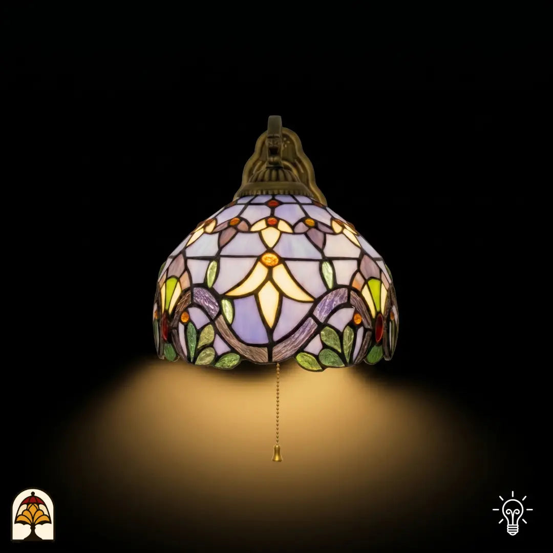 Frontaal aanzicht verlichte Tiffany wandlamp Royal Mosaic, koepelkap in lavendel met crèmegele bloemen en groene bladrand, trekschakelaar zichtbaar