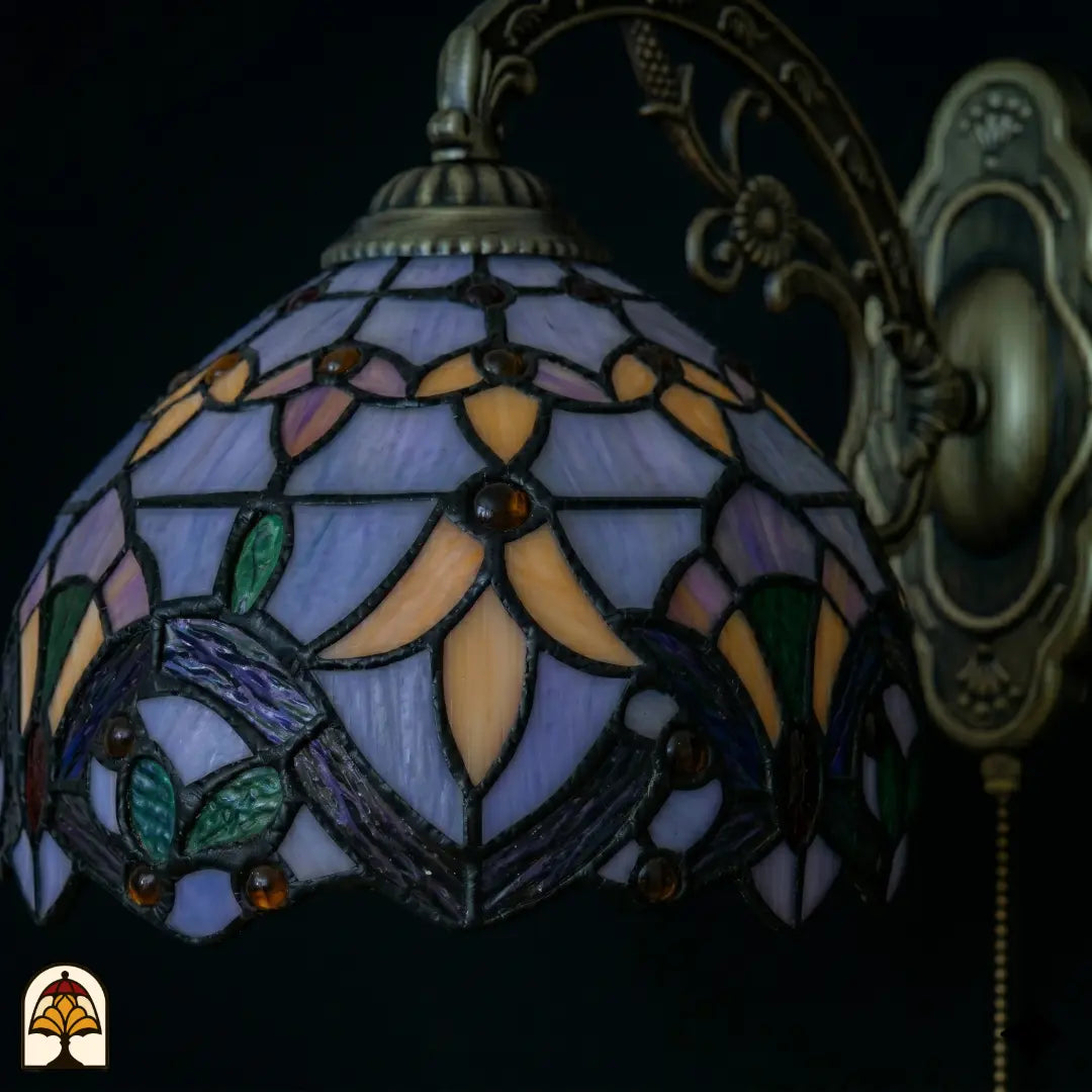 Onverlichte kap Tiffany wandlamp Royal Mosaic close-up – lavendelblauw, oranje en groen glas-in-lood met paarse iris en donkere loodlijnen