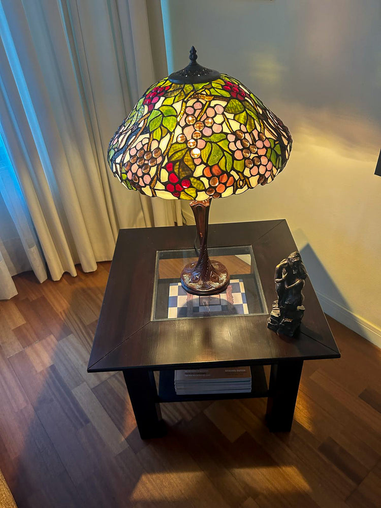 Een ronde tiffany hanglamp met een verfijnd bloemenpatroon in rood en groen glas in lood.