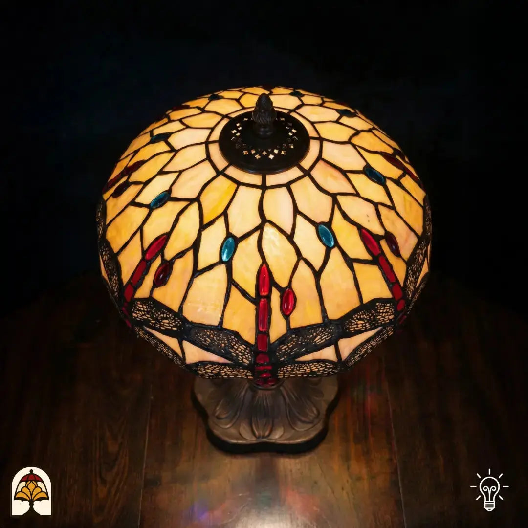 Bovenaanzicht verlichte koepelkap Tiffany tafellamp Libelle Elegance, geel-amber glas-in-lood met rode druppels, blauwe accenten en libellenmotieven, bronzen centrale fitting