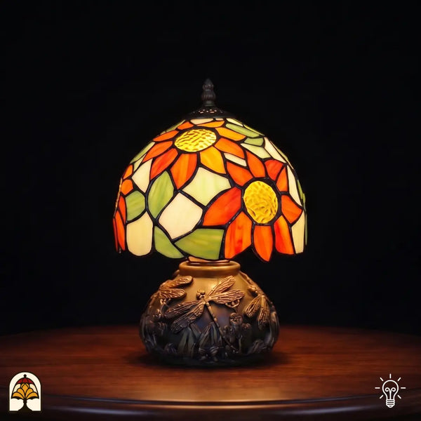 Tiffany tafellamp Solea Radix ⌀20 cm verlicht – bolvormige kap met oranje zonnebloemen en groene bladeren op libellenvoetstuk