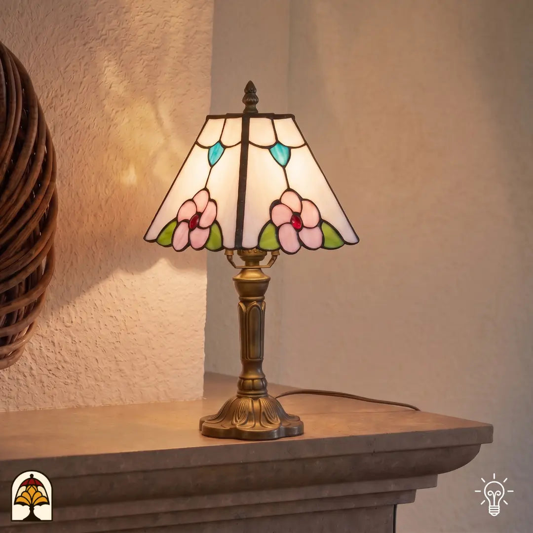 Verlichte Tiffany lamp tafellamp Rosa Zaffiro ⌀20 cm in interieur op houten tafel – crème kap met roze bloemen en blauwe bladaccenten, bronzen voet, warm licht