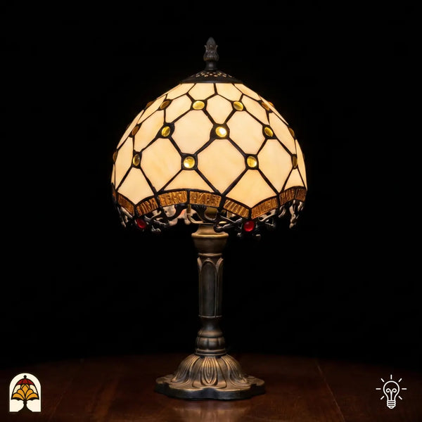 Verlichte Tiffany lamp tafellamp Reticolo d'Oro ⌀20 cm op zwarte achtergrond – crème kap met gouden juwelen en diamantpatroon, bronzen voet