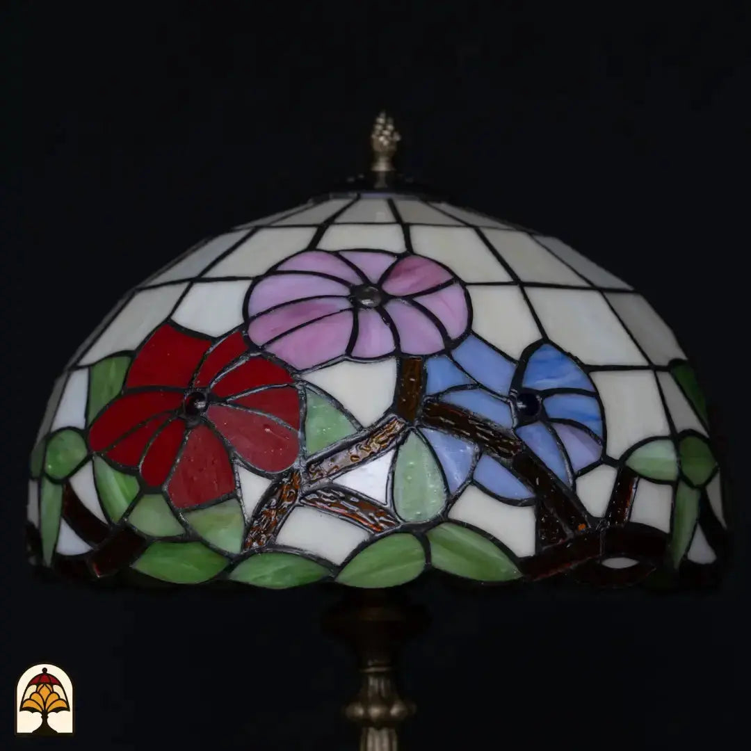 Close-up kap Tiffany tafellamp Aurora Bloom onverlicht — witte achtergrond met roze, rode en blauwe bloemen, gouden/bruine takken, groene bladeren