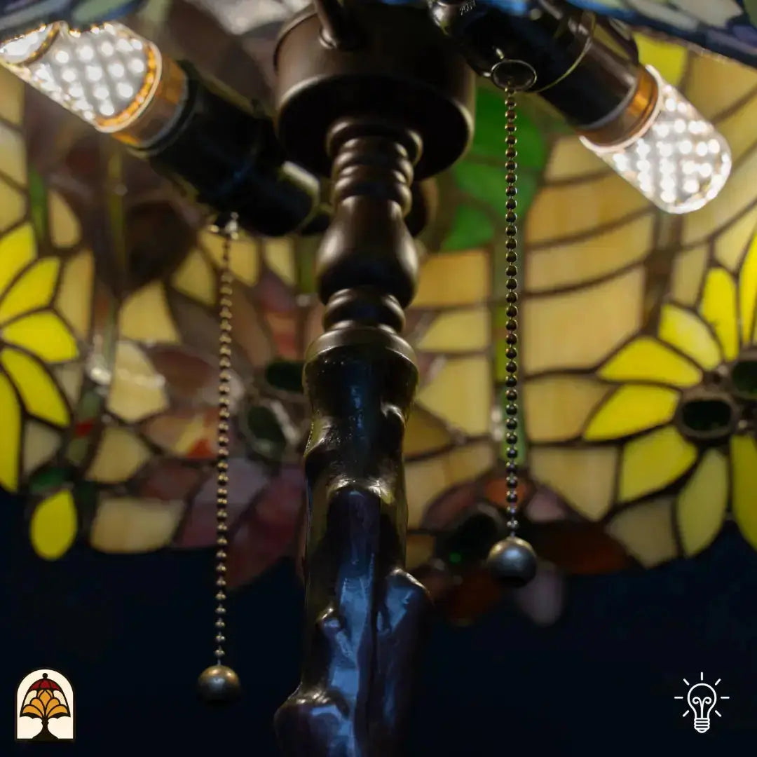 Close-up fitting — twee LED-peertjes in boomstam-stijl bronzen fitting met trekschakelaars, kleurrijk Tiffany glas op achtergrond