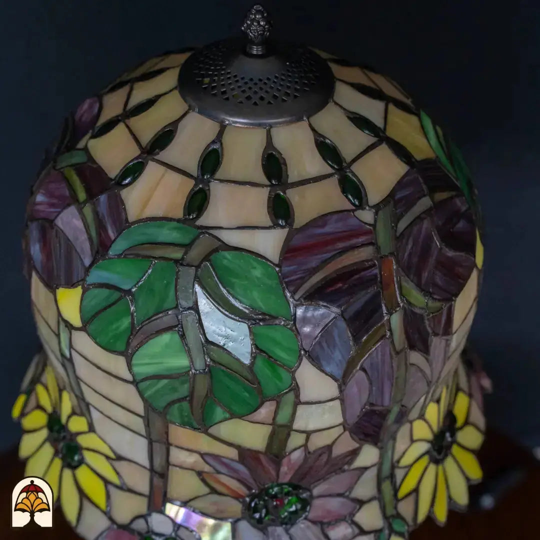 Close-up Tiffany kap onverlicht — bovenkant kap, amber/geel glas met groene decoratieve elementen, paarse en rode bloemen