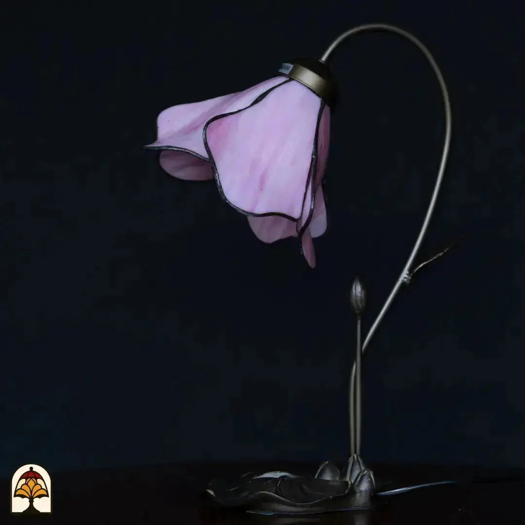 Onverlichte Tiffany tafellamp op donkerblauwe achtergrond — roze lotusbloem kap, gebogen stengel arm met knop, bronzen lotusblad basis
