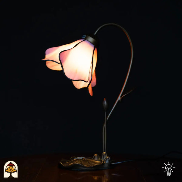 Verlichte Tiffany tafellamp met roze lotusbloem kap, gebogen stengelvormige arm met knop, bronzen lotusblad basis, zwarte achtergrond