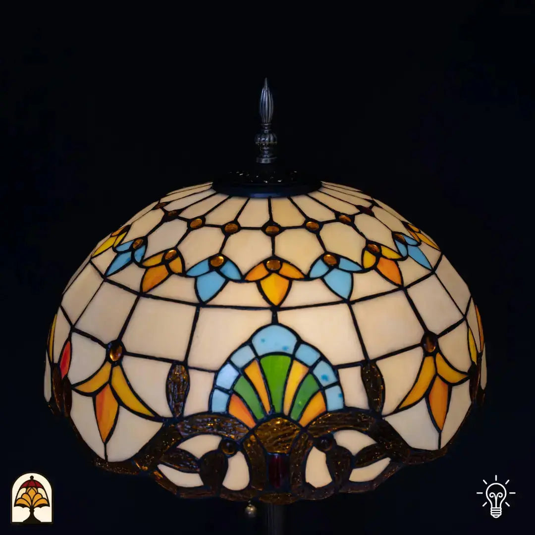 Close-up kap Tiffany vloerlamp Barok andere hoek — crème bovenzijde met blauwe en oranje tulpvormen, groene waaierpatroon onderaan, bronzen decoratieve rand