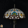 Close-up fitting Tiffany vloerlamp Barok — twee LED-peertjes in bronzen dubbele fitting, twee trekschakelaars, kleurig glas kap op achtergrond