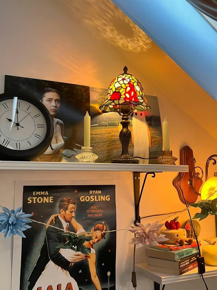 Tiffany tafellamp met oranje glas-in-lood kap met appel- en druivenmotieven, warm decoratief sfeerlicht voor een klassiek interieur.