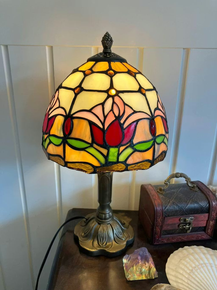 Tiffany tafellamp met rood en geel glas-in-lood kap met tulpenmotief, warm sfeervol licht voor een klassiek interieur.