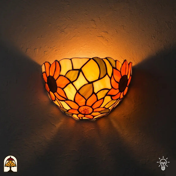 Tiffany wandlamp Solea Girasole verlicht op muur – halfronde kap met zonnebloemen in oranje en geel glas